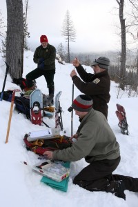 Biologists preparing the drugs to sedate the bear. They staged away from the den, visible behind the farthest biologist, to minimize noise.