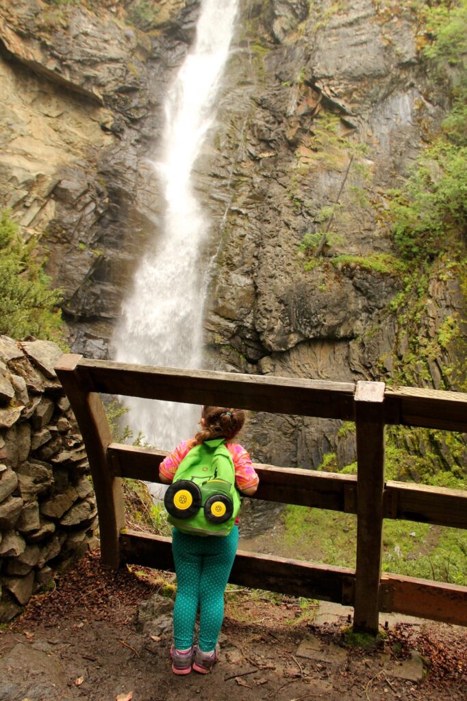 Young girl carrying backpack looks at Copper Creek Falls.